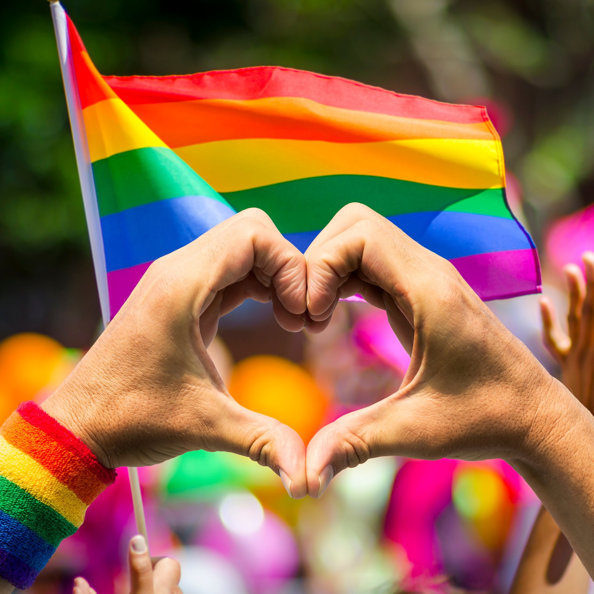 Hands making a heart in front of a rainbow flag - AdobeStock 158473739