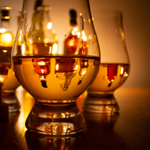 Three whisky glasses and reflecting bottles