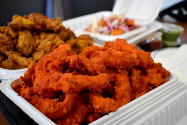 Fish Pakoras in a white take out container. Tandoori Chicken on the Street Food Trail